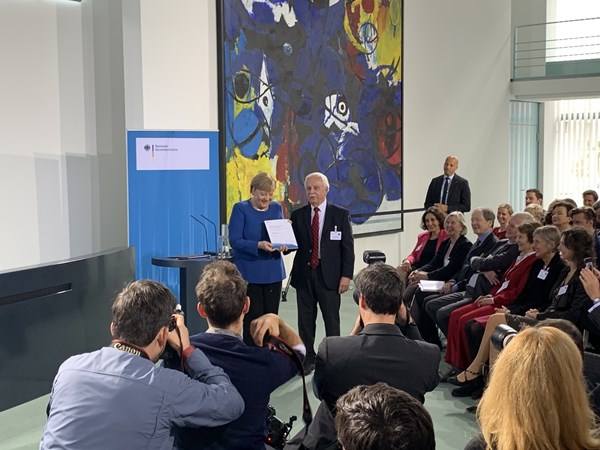 Dr. Johannes Ludewig übergibt Angela Merkel den Jahresbericht 2019.